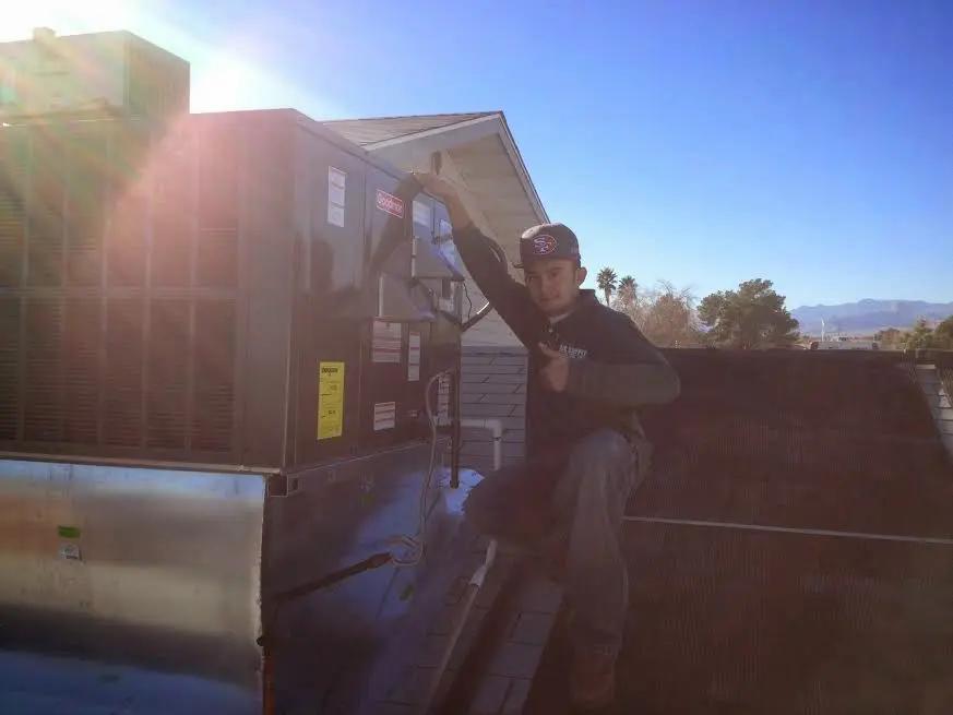 HVAC technician performing Heat Pump Repair on a rooftop unit in Webb City